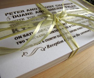 Stack of Fontography inspired laser cut wedding invitations with yellow ribbon